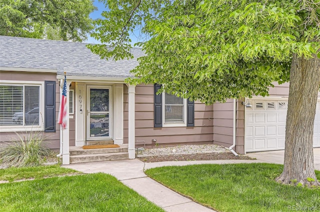 1697 W Powers Ave, Littleton, CO 80120 - property entrance featuring roof with shingles, a yard, and a garage