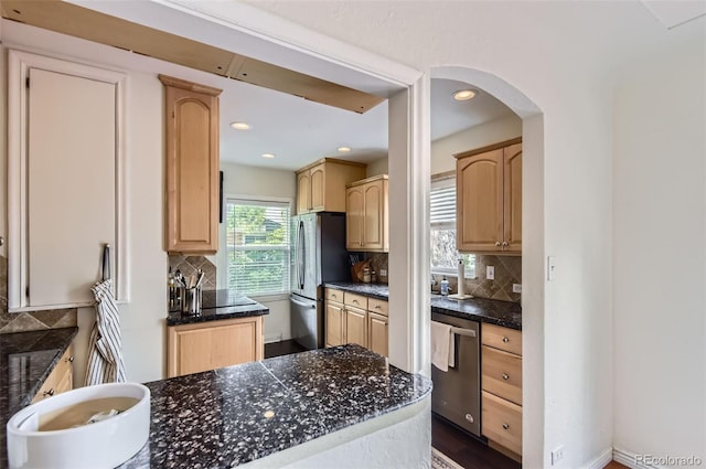 1697 W Powers Ave, Littleton, CO 80120 - kitchen featuring appliances with stainless steel finishes, dark countertops, light brown cabinets, tasteful backsplash, and arched walkways