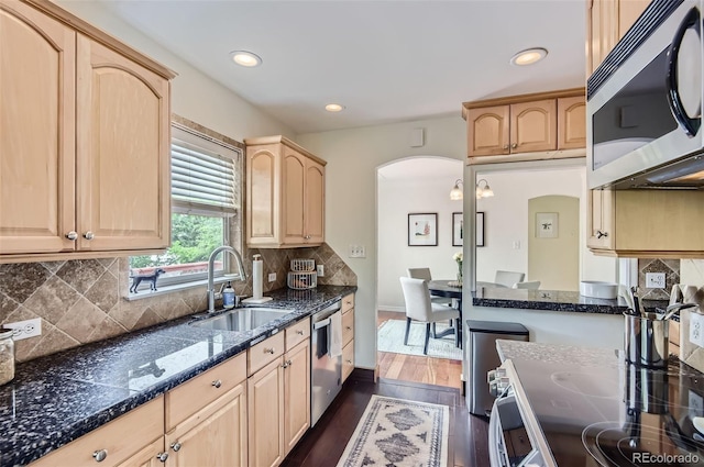 1697 W Powers Ave, Littleton, CO 80120 - kitchen with appliances with stainless steel finishes, a sink, arched walkways, light brown cabinetry, and dark wood finished floors