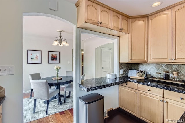 1697 W Powers Ave, Littleton, CO 80120 - kitchen with light brown cabinetry, tasteful backsplash, a chandelier, dark wood finished floors, and dark stone counters