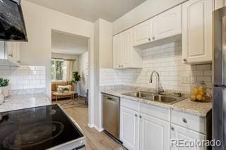 kitchen featuring backsplash, white cabinetry, light hardwood / wood-style flooring, and stainless steel appliances