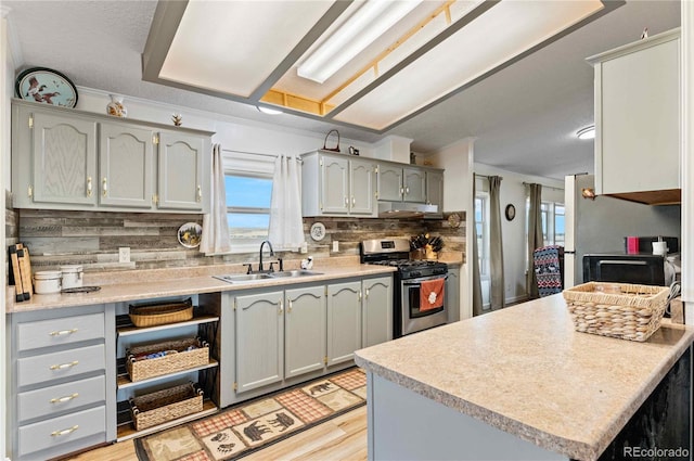 kitchen featuring gray cabinetry, backsplash, sink, light wood-type flooring, and gas stove