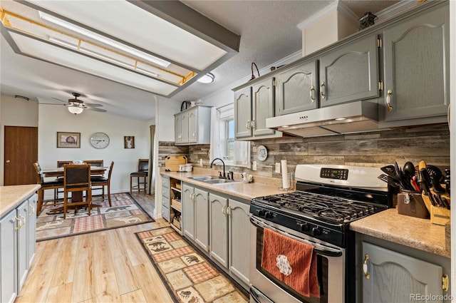 kitchen with gas range, ceiling fan, sink, gray cabinetry, and light wood-type flooring