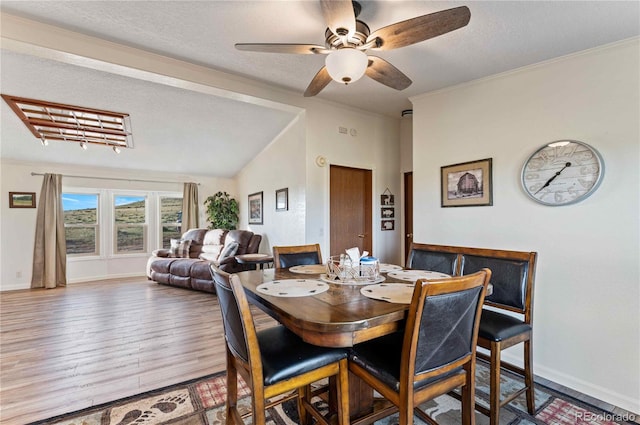 dining room with vaulted ceiling, ceiling fan, wood-type flooring, and a textured ceiling