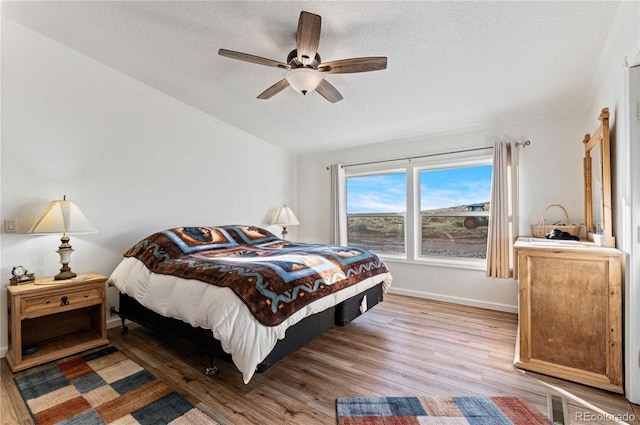 bedroom featuring a textured ceiling, light hardwood / wood-style floors, and ceiling fan