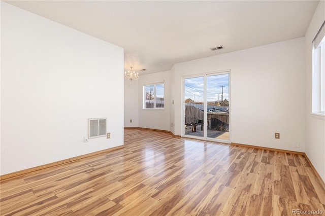 unfurnished room with light wood-type flooring and an inviting chandelier