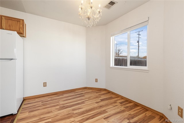 unfurnished dining area with light hardwood / wood-style flooring and an inviting chandelier