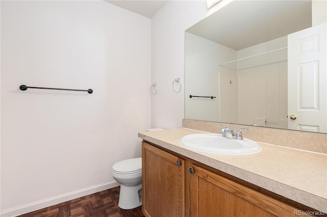 bathroom with vanity, toilet, parquet flooring, and a shower