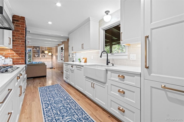 5465 W Ontario Ave, Littleton, CO 80128 - kitchen featuring ventilation hood, backsplash, light countertops, light wood-type flooring, and recessed lighting