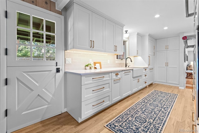 5465 W Ontario Ave, Littleton, CO 80128 - kitchen with light countertops, decorative backsplash, light wood-style floors, white cabinetry, and recessed lighting