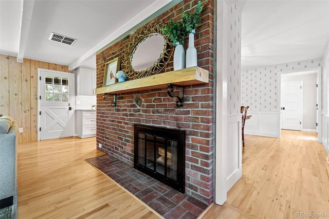 5465 W Ontario Ave, Littleton, CO 80128 - living room featuring a brick fireplace, light wood-style flooring, a decorative wall, and beamed ceiling
