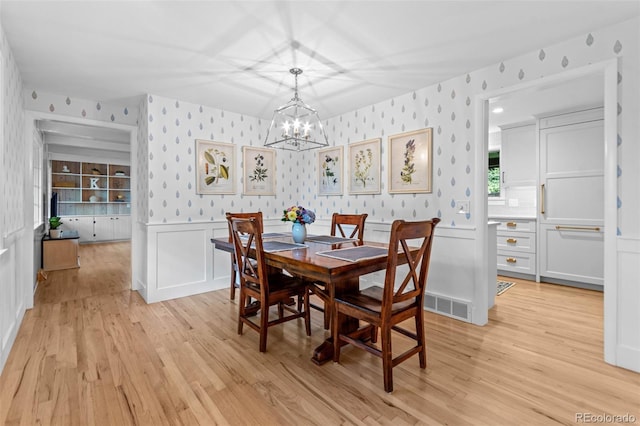 5465 W Ontario Ave, Littleton, CO 80128 - dining room with wallpapered walls, light wood-style flooring, a chandelier, and a wainscoted wall