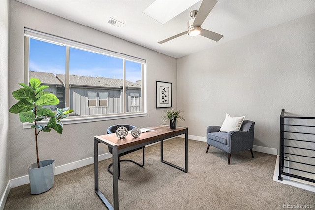 office space featuring carpet, ceiling fan, and a skylight