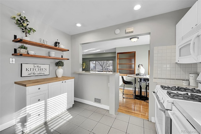 kitchen featuring white cabinetry, wood counters, backsplash, white appliances, and light tile patterned floors