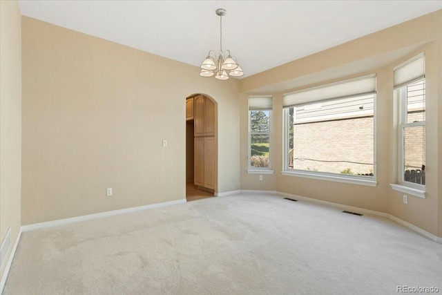 6449 S Jamaica Cir, Englewood, CO 80111 - empty room featuring arched walkways, light colored carpet, and a chandelier