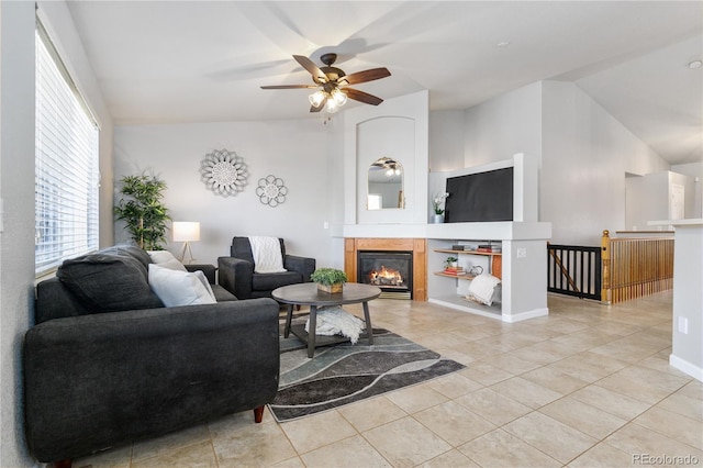 living room featuring a ceiling fan, lofted ceiling, a glass covered fireplace, and light tile patterned floors