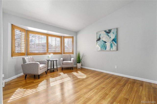 sitting room featuring light wood-style floors, vaulted ceiling, and baseboards