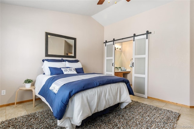 bedroom featuring lofted ceiling, light tile patterned floors, baseboards, and a barn door