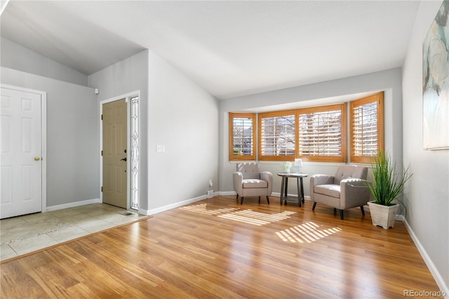 unfurnished room with baseboards, vaulted ceiling, and wood finished floors