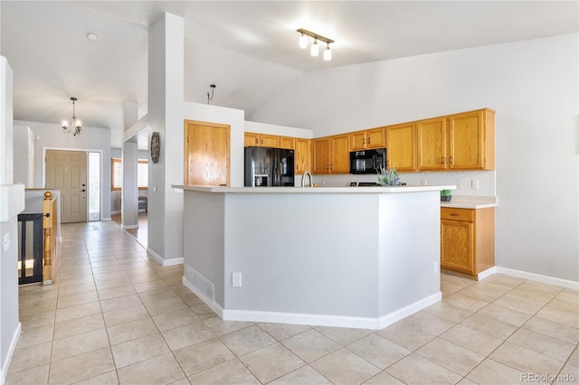 kitchen featuring light tile patterned floors, light countertops, backsplash, vaulted ceiling, and black appliances