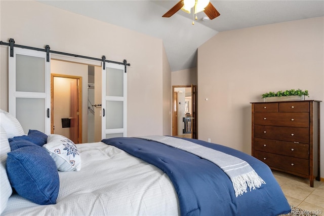 bedroom with ceiling fan, light tile patterned floors, vaulted ceiling, and a barn door