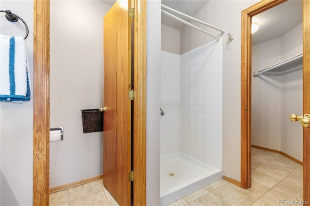 bathroom featuring a stall shower, tile patterned flooring, and baseboards