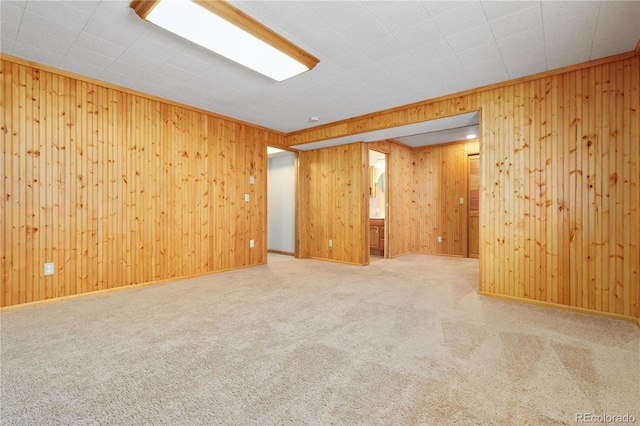 carpeted empty room featuring wood walls and baseboards