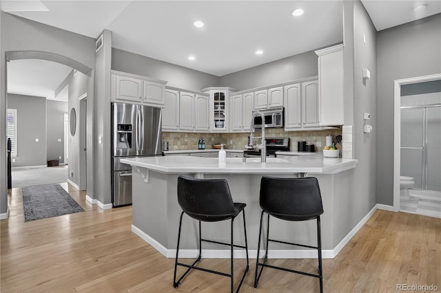 8378 Briar Trace Way, Castle Pines, CO 80108 - kitchen featuring appliances with stainless steel finishes, arched walkways, a kitchen bar, a peninsula, and backsplash