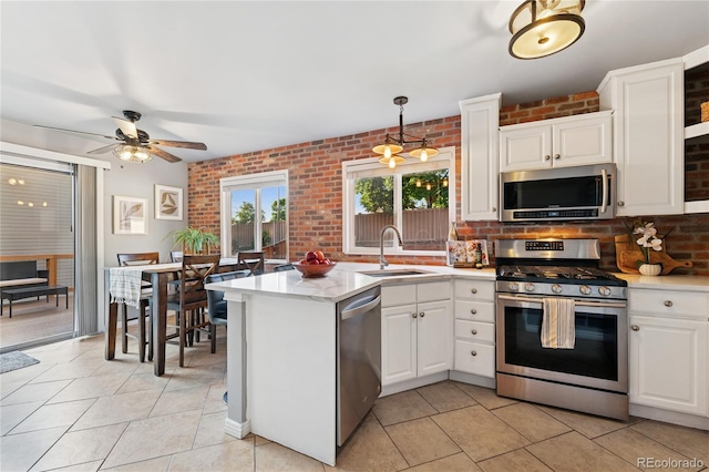 561 James St, Highlands Ranch, CO 80126 - kitchen featuring stainless steel appliances, brick wall, light countertops, light tile patterned floors, and white cabinets