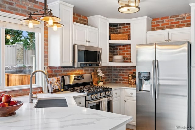 561 James St, Highlands Ranch, CO 80126 - kitchen featuring stainless steel appliances, brick wall, white cabinets, and light stone countertops