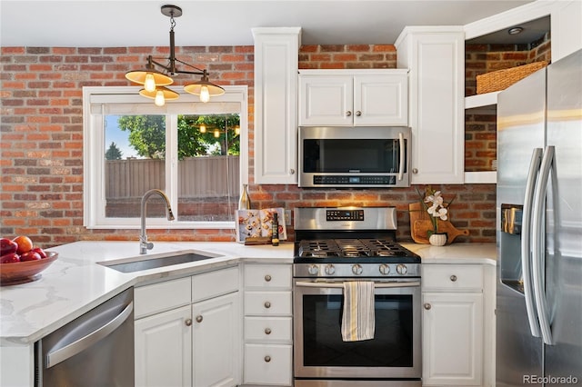 561 James St, Highlands Ranch, CO 80126 - kitchen with stainless steel appliances, brick wall, white cabinets, hanging light fixtures, and light stone countertops