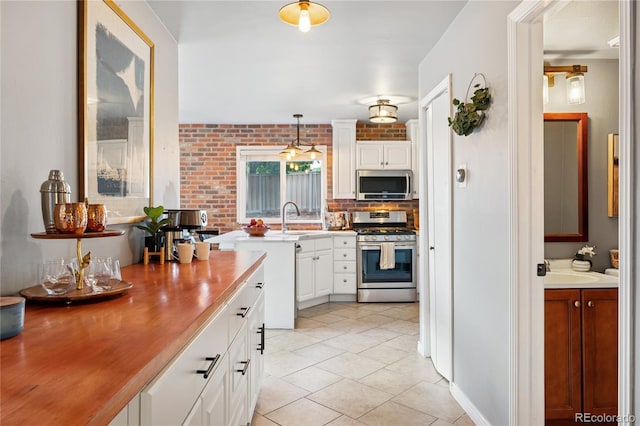 561 James St, Highlands Ranch, CO 80126 - kitchen featuring stainless steel appliances, white cabinets, light tile patterned flooring, light countertops, and decorative light fixtures