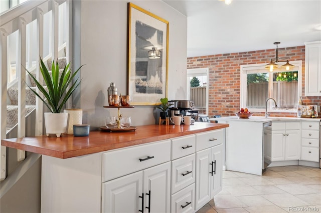 561 James St, Highlands Ranch, CO 80126 - kitchen featuring brick wall, white cabinetry, light tile patterned floors, stainless steel dishwasher, and hanging light fixtures