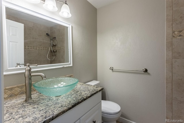 full bath featuring toilet, vanity, and a tile shower