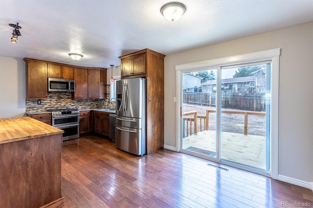 kitchen featuring visible vents, dark wood-type flooring, appliances with stainless steel finishes, decorative backsplash, and wooden counters