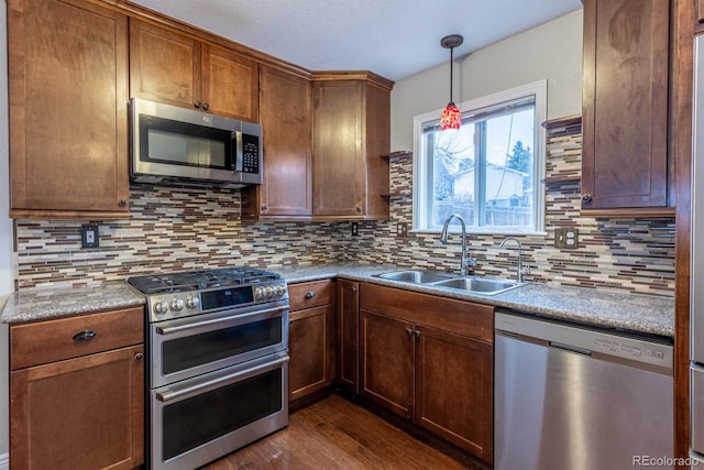 kitchen with dark wood finished floors, backsplash, stainless steel appliances, and a sink