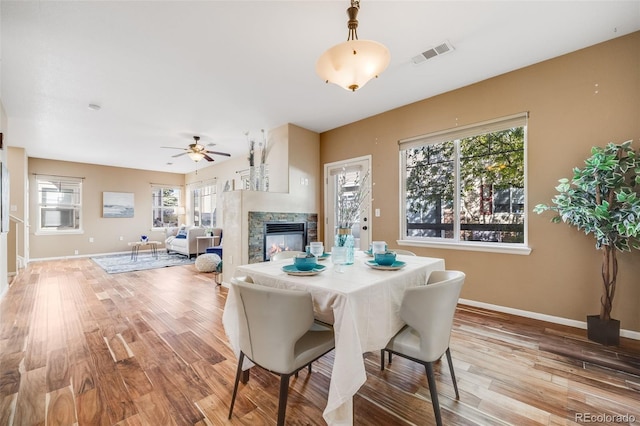 dining room with a premium fireplace, light wood-style flooring, plenty of natural light, and baseboards
