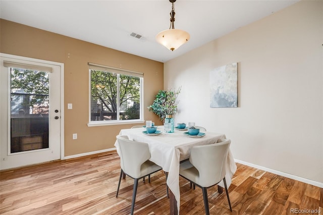 dining space with light wood-type flooring and baseboards