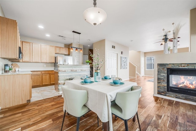dining space featuring light wood-type flooring, a ceiling fan, a fireplace, recessed lighting, and baseboards