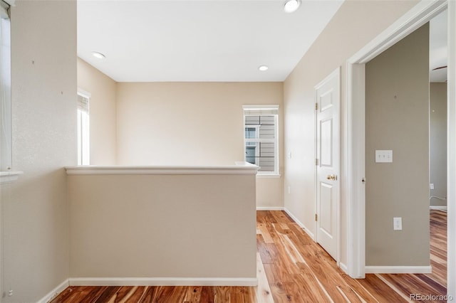 hallway with light wood-style flooring, baseboards, and recessed lighting