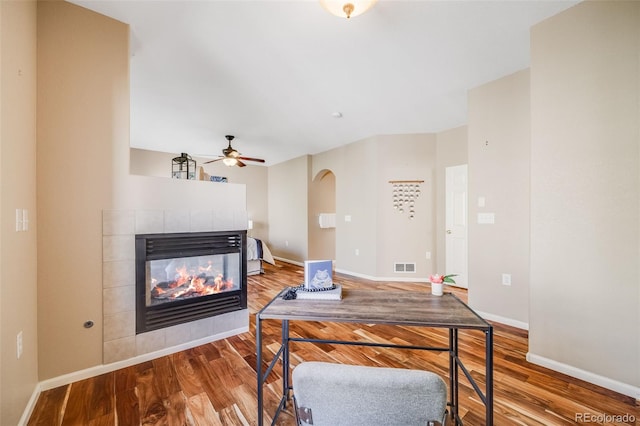 office with wood finished floors, a fireplace, ceiling fan, and baseboards
