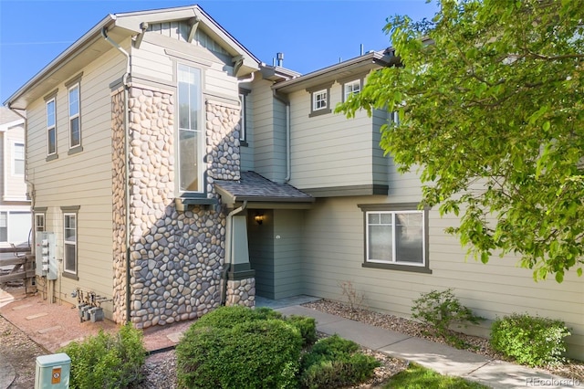 view of front of house featuring stone siding and roof with shingles