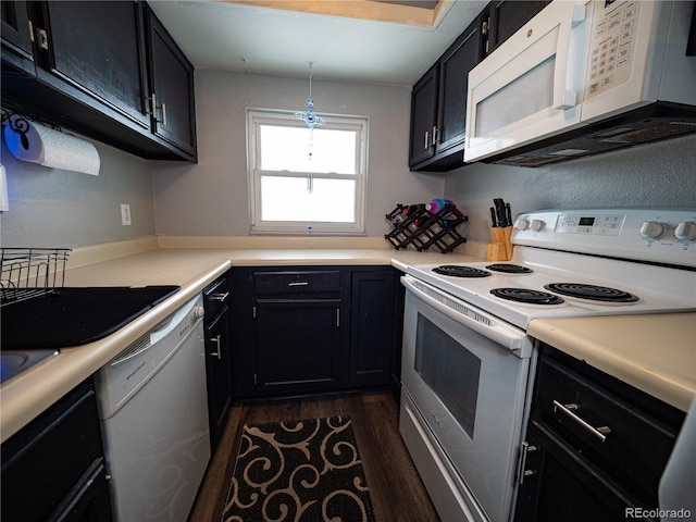 kitchen with decorative light fixtures, white appliances, and dark wood-type flooring