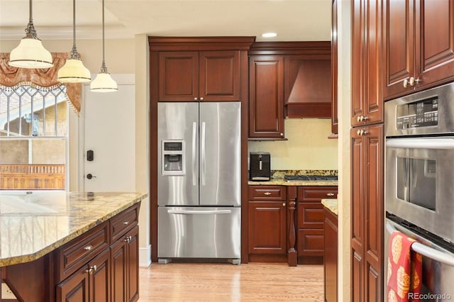 2006 N Cascade Ave, Colorado Springs, CO 80907 - kitchen featuring custom exhaust hood, stainless steel appliances, light wood-type flooring, reddish brown cabinets, and pendant lighting