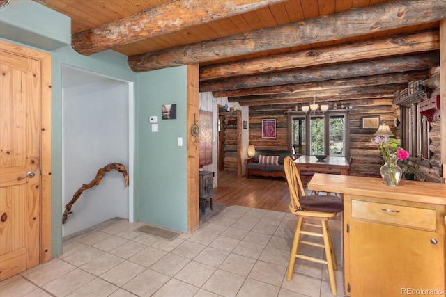 18680 Wapiti Cir, Buena Vista, CO 81211 - dining room featuring log walls, a wooden ceiling with exposed beams, a wood stove, and light tile patterned flooring
