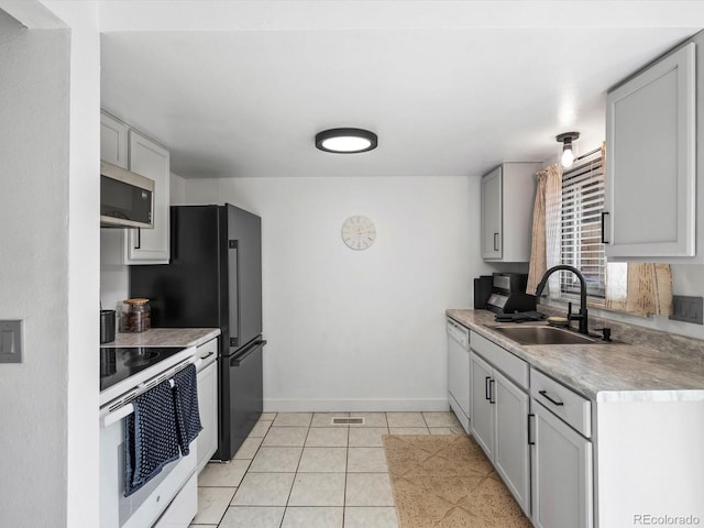 kitchen with light tile patterned flooring, white appliances, a sink, baseboards, and light countertops