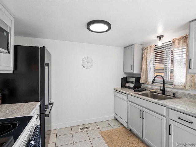 kitchen with light tile patterned floors, light countertops, a sink, and appliances with stainless steel finishes