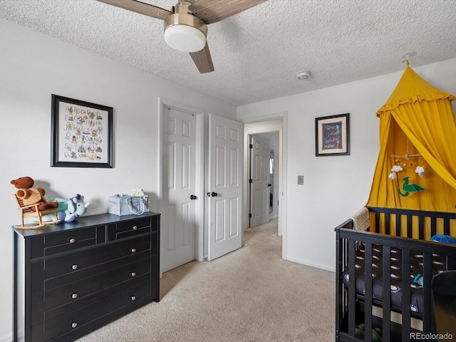 bedroom featuring light carpet, a textured ceiling, and ceiling fan
