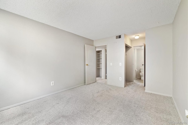 15202 E Hampden Cir Unit F2, Aurora, CO 80014 - unfurnished bedroom with carpet flooring, a textured ceiling, a spacious closet, ensuite bathroom, and a closet