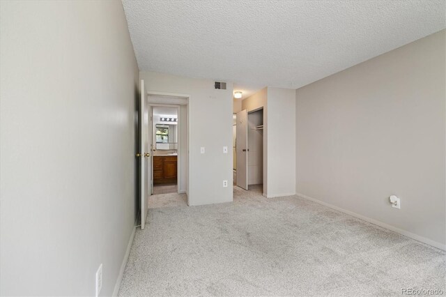 15202 E Hampden Cir Unit F2, Aurora, CO 80014 - unfurnished bedroom with light colored carpet, a textured ceiling, and a closet